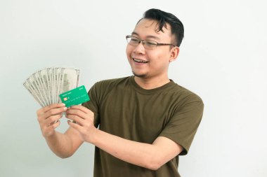 Mutlu Asyalı adamın kredi kartı ve parası var. Bankacılık, finansal izole, yeşil renk konsepti