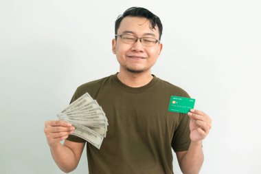 Mutlu Asyalı adamın kredi kartı ve parası var. Bankacılık, finansal izole, yeşil renk konsepti