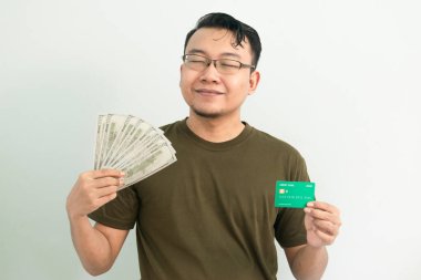 Mutlu Asyalı adamın kredi kartı ve parası var. Bankacılık, finansal izole, yeşil renk konsepti