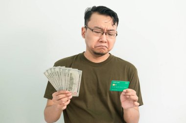Üzgün Asyalı adamın kredi kartı ve parası var. Bankacılık, finansal izole, yeşil renk konsepti