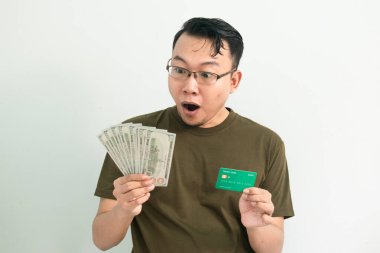 Asyalı adamın elinde para ve kredi kartı olmasına şaşırdım ve gülümsedim. Bankacılık, finansal izole, yeşil renk konsepti