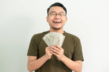 Mutlu Asyalı adam göğsünde para tutuyor ve zevk alıyor. Bankacılık, finansal izole, yeşil renk konsepti
