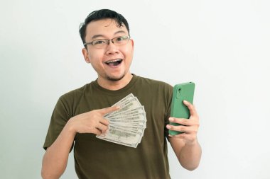 Mutlu Asyalı adam Para 'yı ve telefonu tutuyor. Bankacılık, finans ve teknoloji izole edilmiş, yeşil renk kavramı