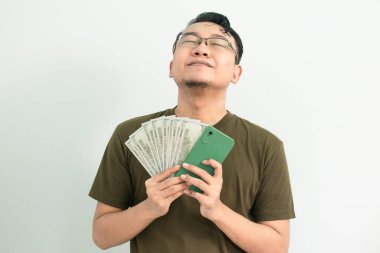 Mutlu Asyalı adam para ve telefondan kurtulmuş hissediyor. Bankacılık, finans ve teknoloji izole edilmiş, yeşil renk kavramı