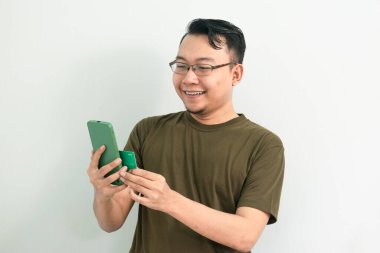 Asyalı adam kredi kartı ve telefonla işlem yapıyor. Bankacılık, finans ve teknoloji izole edilmiş, yeşil renk kavramı