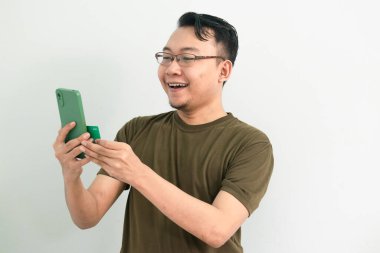 Asyalı adam kredi kartı ve telefonla işlem yapıyor. Bankacılık, finans ve teknoloji izole edilmiş, yeşil renk kavramı