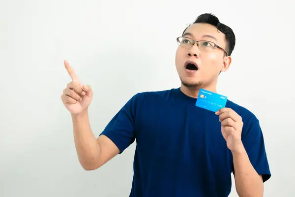 Asyalı adamın kredi kartında işaret pozu olmasına şaşırdım. Bankacılık, finansal izole, mavi renk konsepti