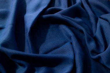 Donanma veya koyu mavi kumaş dalgalı sarmal buruşuk arkaplan dokusu ve merkezinde kopya alanı var..