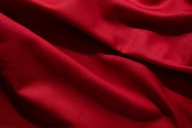 Buruşuk dalgalı kırmızı ipeksi kumaş arkaplan dokusunu kapat. sinsi ve ışıltılı.