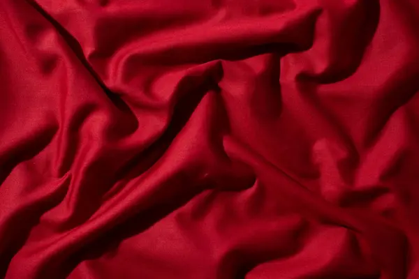 Buruşuk dalgalı kırmızı ipeksi kumaş arkaplan dokusu. sinsi ve ışıltılı.