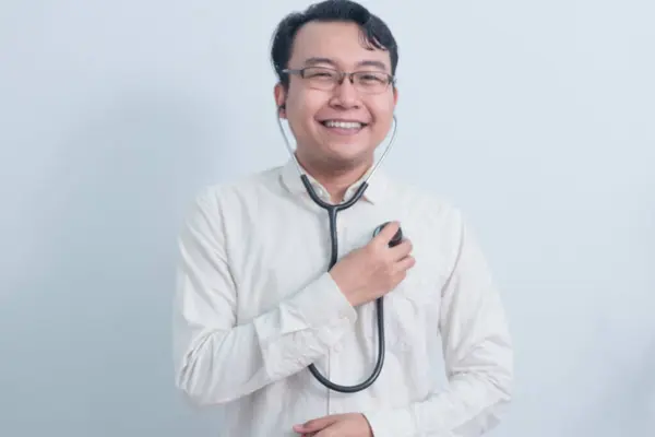 Neşeli Asyalı erkek doktor, erkek hemşire göğsüne steteskop kullanıyor..