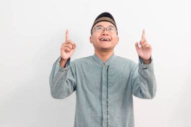 Asyalı Müslüman adam gülümseyip Ramazan Bayramı 'nda ve Kurban Bayramı' nda izole edilmiş beyaz arka planı kutluyor. İslami kutlama kavramı.