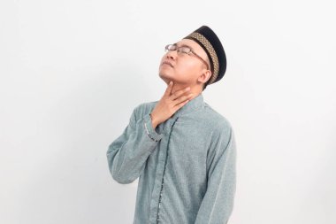 Asyalı Müslüman bir adam boynuna dokunuyor, Ramazan Bayramı 'nda susamış bir jest yapıyor ve Kurban Bayramı' nda izole edilmiş beyaz arka planı kutluyor. İslami kutlama kavramı.