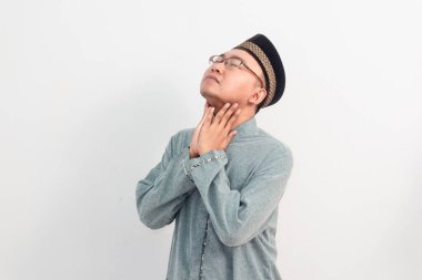 Asyalı Müslüman bir adam boynuna dokunuyor, Ramazan Bayramı 'nda susamış bir jest yapıyor ve Kurban Bayramı' nda izole edilmiş beyaz arka planı kutluyor. İslami kutlama kavramı.