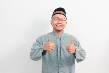 Asyalı Müslüman adam Ramazan Bayramı 'nda el işareti yapıyor ve Kurban Bayramı' nda izole edilmiş beyaz arka planı kutluyor. İslami kutlama kavramı.