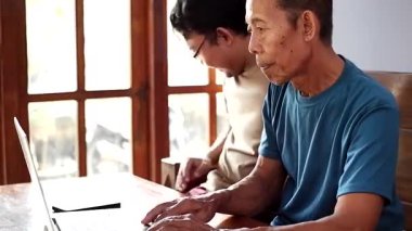 Mutlu yetişkin oğul yaşlı babaya dizüstü bilgisayar öğretiyor. Genç ve kıdemli birliktelik konsepti