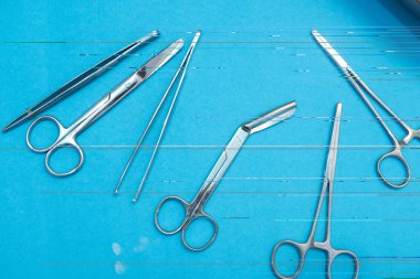 Mavi arka planda cerrahi alet seti. Makas ve forseps de dahil. Tıbbi malzemeler...