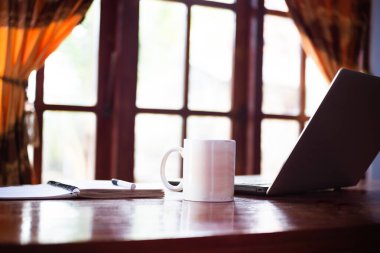 Oturma odasında kitap, dizüstü bilgisayar ve bir fincan kahve olan kimse yok. Boş oda ekranı