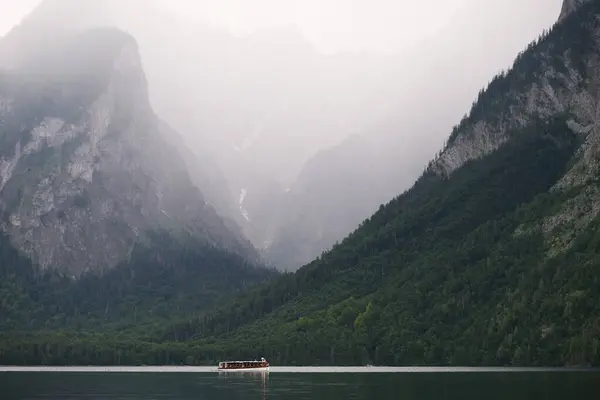 Görüntü, dağlarla göl arasında, sahil boyunca tekneleri ve binaları olan pitoresk bir Hallstatter kasabasını gösteriyor..