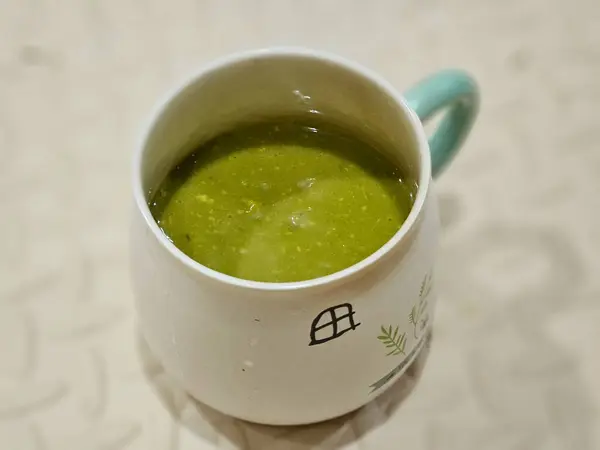 Close up of a cup of avocado juice on beige wood and blurred background