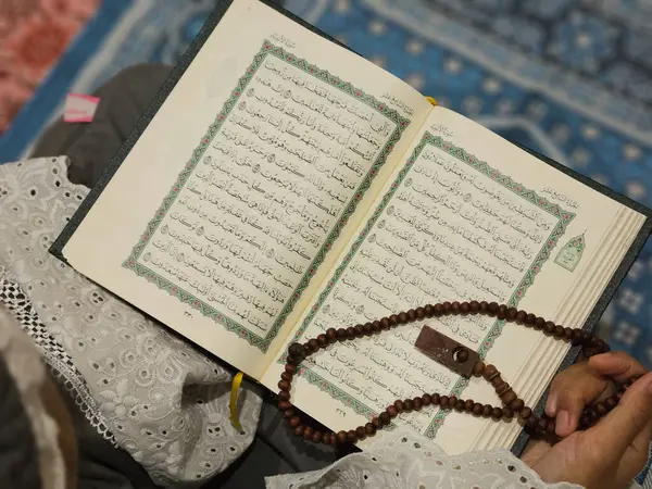 Genç bir Asyalı Müslüman kadın, Ramazan ayında bir camide namaz kılıyor ve Kuran okuyor..