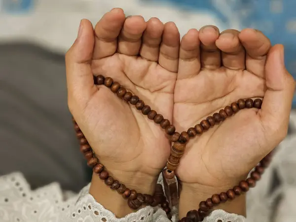 Genç bir Asyalı Müslüman kadın Ramazan ayı boyunca tespih tutar ve dua eder.
