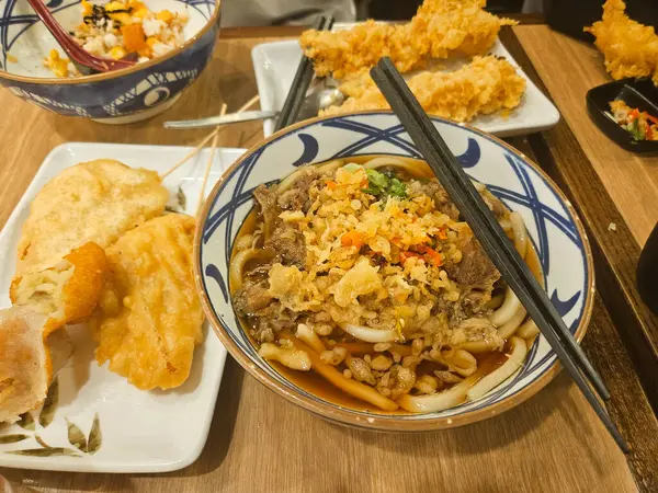 Geleneksel Japon erişte çorbası Niku Udon biftekli sukiyaki, tempura ve dilimlenmiş taze soğan ve biberli