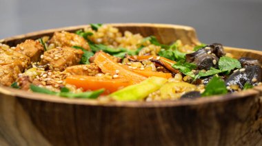 Tahta bir kasede servis edilen sebzeli Tayland usulü tavuk.