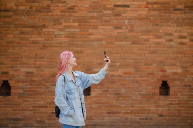 Pembe saç stili olan şık bir genç kadın selfie çekiyor. Yüksek kalite.