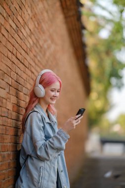 Woman in pink hair using smartphone on the street clipart