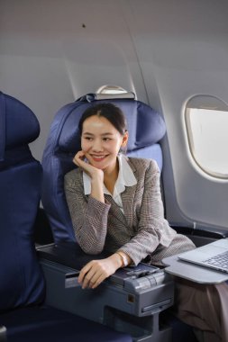 Uçakta dizüstü bilgisayar kullanan Asyalı bir kadın iş seyahati ve teknoloji kavramı. Yüksek kalite fotoğraf