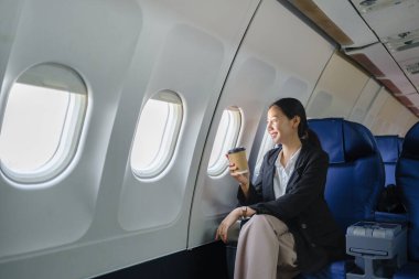 Havaalanında pencereden gökyüzü manzaralı genç bir iş kadını oturmuş bir fincan kahve içiyor. Yüksek kalite fotoğraf