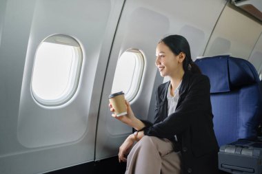 Havaalanında pencereden gökyüzü manzaralı genç bir iş kadını oturmuş bir fincan kahve içiyor. Yüksek kalite fotoğraf