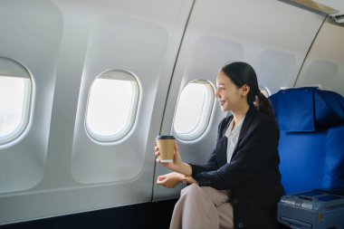 Havaalanında pencereden gökyüzü manzaralı genç bir iş kadını oturmuş bir fincan kahve içiyor. Yüksek kalite fotoğraf