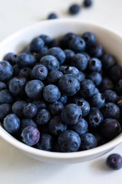 Beyaz bir masada beyaz bir kasede taze yaban mersini..