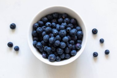 Beyaz bir masada beyaz bir kasede taze yaban mersini..