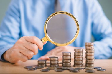 Faiz artışı, temettüel para yatırımı kavramı. Finansal hizmetlerin iş koşulları. Adam ev kredisi faiz yüzdesi ikonu ve ipotek oranı gayrimenkul üzerinde büyüteç kullanıyor 