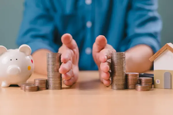 Boşanma hukuku ve miras ayrılığı kavramı. El ile tasarruf parası, finans, ev kredisi, domuz kumbarası ve ahşap ev borcu. Banka işi yatırımı. Adam masaya bozuk para yığıyor.