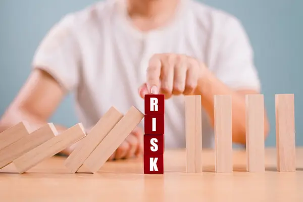 Risk yönetimi kriz konsepti. Emlak işi için finansal analiz çözümü. Elle durdurma ekonomik risk. Tahta blokta risk kelimesi, domino krizi etkisini azaltır. Sigorta güvenlik değerlendirmesi