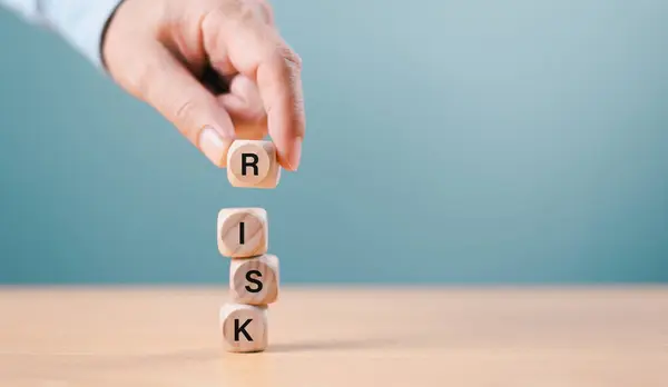 Risk yönetimi kriz konsepti. Finansal analiz çözümü, emlak işi. Ekonomik risk üzerine işadamı eli tahta blokta, domino krizinde. Sigorta değerlendirmesi, mavi arkaplan