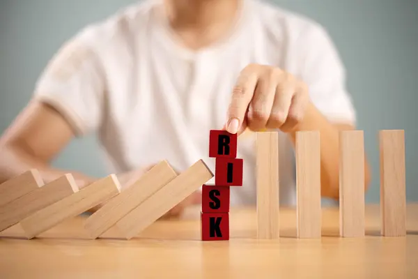 Risk yönetimi kriz konsepti. Emlak işi için finansal analiz çözümü. Elle durdurma ekonomik risk. Tahta blokta risk kelimesi, domino krizi etkisini azaltır. Sigorta güvenlik değerlendirmesi