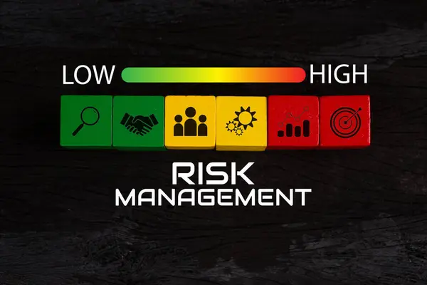 Risk yönetimi konsepti. Risk değerlendirme seviyesi göstergesi derecesi. İş değerlendirmesi ölçüsü. Yeşil üzerine kırmızı ok işareti, sarı renkli tahta blok, yüksek simgeye yakın, siyah arkaplan. Üst görünüm 
