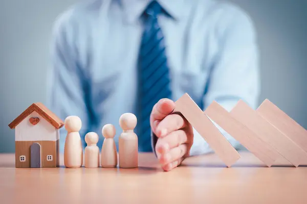 Sigorta finansmanı ev kredisi kavramını korur. Güvenli aile için ev kredisi. İş adamı el güvenliği risk değerlendirmesi yapıyor, tahta domino bloğu. Mutlu ev, hayatı koru. Anne ve baba.