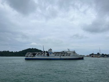 Geminin tepesinde dağ zeminli karanlık gökyüzü olan deniz manzarası.