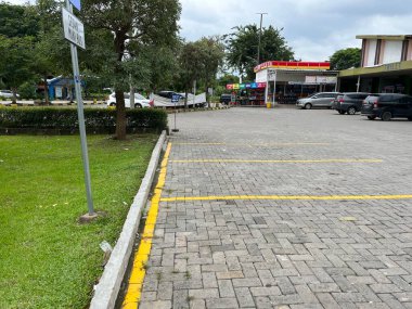 Siyah ve sarı çizgili kaldırımlı otoparklı dinlenme alanı.