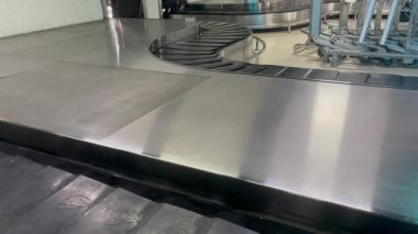Lojistik Ulaşım için Modern Seyahat Terminalindeki Havaalanı Bagaj Atlıkarıncasında. Havaalanı terminali içinde sessiz, boş bir bagaj atlıkarınca. Paslanmaz çelik yüzeyler ve taşıma bantları seyahat altyapısı, lojistik ve ulaşımı temsil etmektedir..
