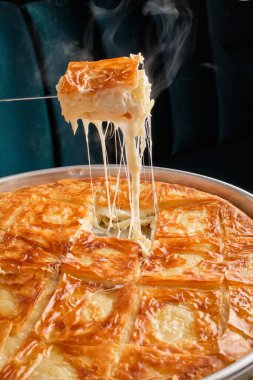 Beyaz bir zeminde, gümüş ve bakır çatal bıçaklarla çevrili beyaz bir tabakta fıstıklı doğu tatlıları.