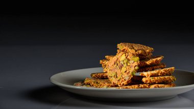 Beyaz arka planda ve gri ve siyah arkaplanda fıstıklı bir tabak Arap tatlısı.