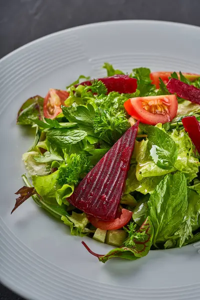 İçinde marul, domates, kırmızı pancar ve nane olan bir salata tabağının yakın plan fotoğrafı.