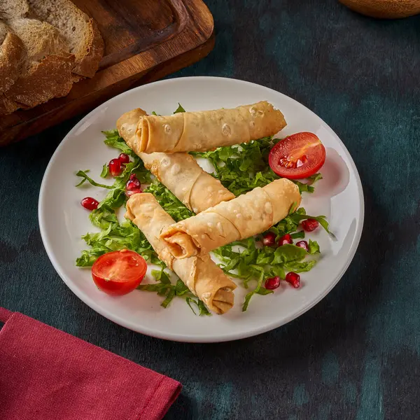 Ahşap zeminde kızartılmış borek sigara aperatifi tabağı.